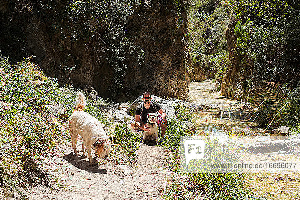 Junger Mann am Fluss mit zwei Hunden im Sommer