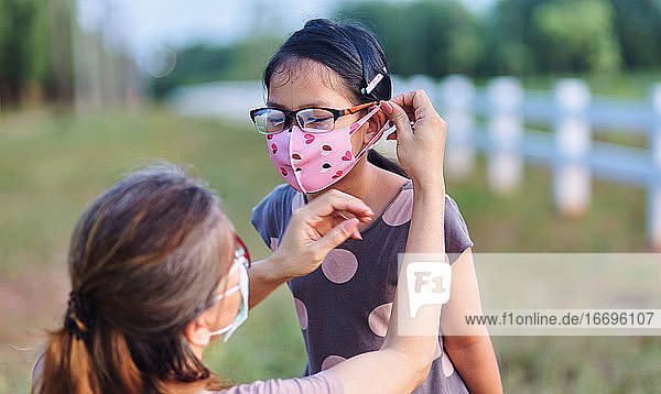 Die Mutter trug eine Maske für ihre Tochter  als sie während des COVID 19 ausging