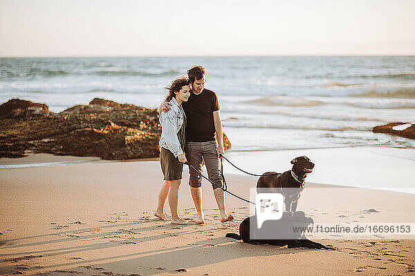 Weitwinkelansicht eines Millennial-Paares  das mit Hunden am Ufer steht