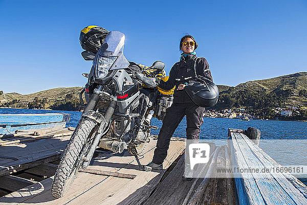 Frau und ihr Reisemotorrad auf einer einfachen Fähre über den Titicacasee