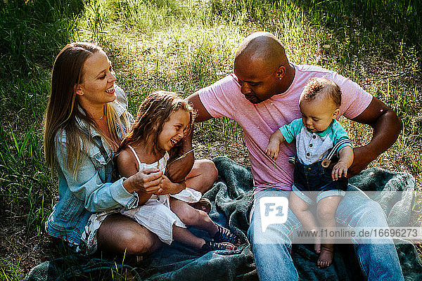 Happy young family laughing and smiling while sitting in grass