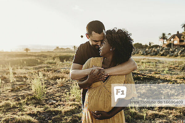Junges Ehepaar umarmt die Schwangerschaft am Strand