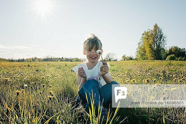 junges Mädchen hält fröhlich eine Blume in einem Blumenfeld im Sommer