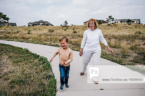 Grandmother chasing smiling grandson outside on a cloudy day