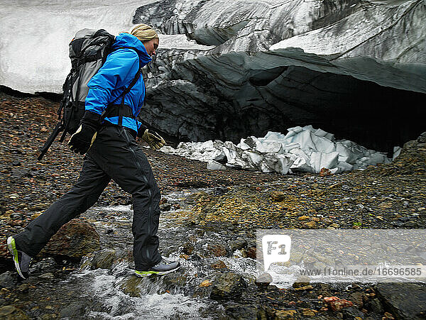Junge Frau beim Überqueren des Flusses Hrafntinnusker in Island