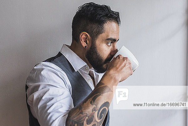 Gutaussehender Mann  gekleidet als Manager  trinkt Kaffee