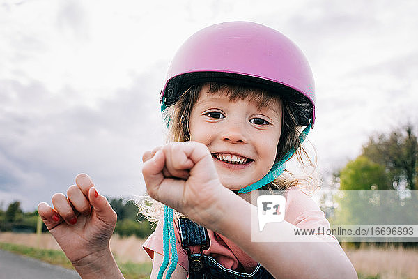 fröhliches Porträt eines jungen Mädchens mit Helm  das draußen spielt