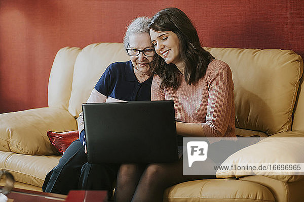 Enkelin zeigt ihrer Großmutter etwas auf dem Laptop