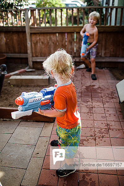 Brothers Playing with Water Guns in Front Yard