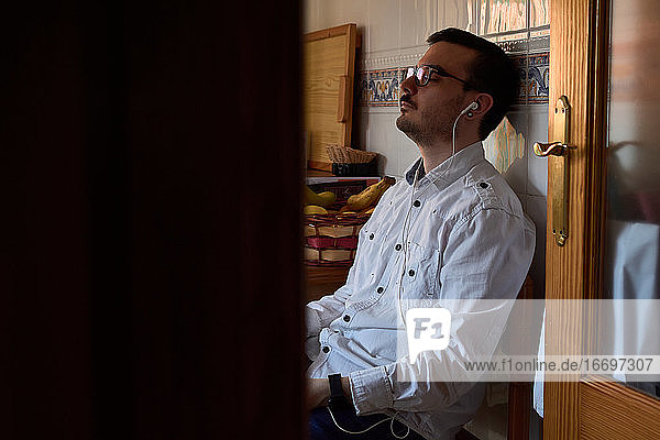 Ein junger Mann hört mit seinen Kopfhörern Musik  während er zu Hause sitzt