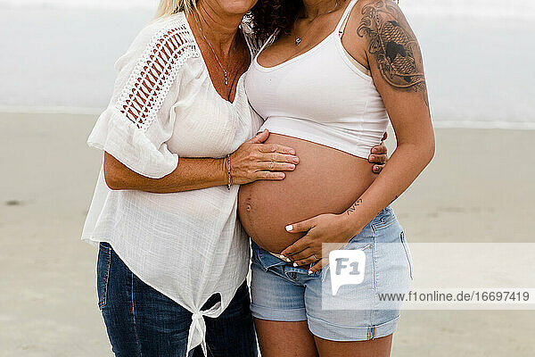 Mom and Pregnant Daughter Embrace  Baby Belly Close Up