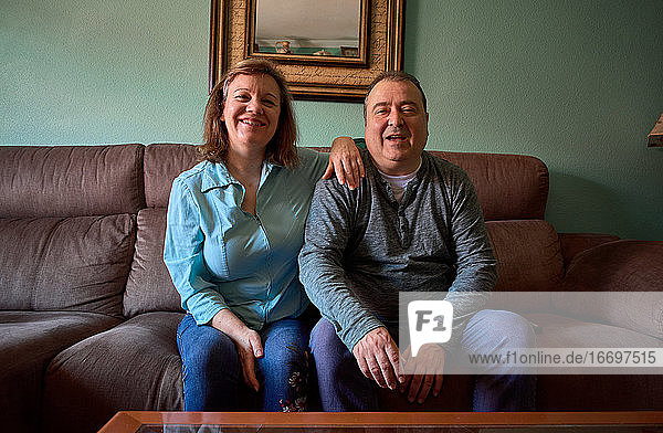 Ein Paar mittleren Alters posiert und lächelt für ein Foto zu Hause