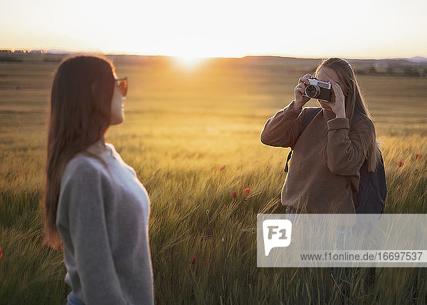zwei Frauen halten sich bei Sonnenuntergang auf einem Feld an den Händen