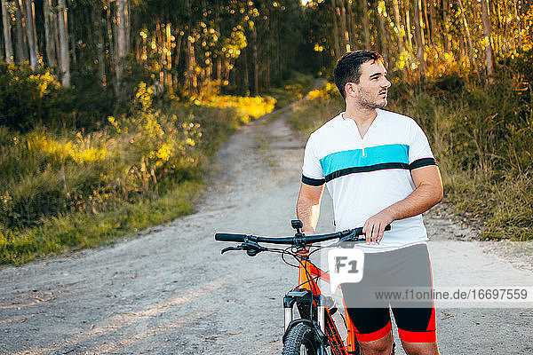Sportswear young man pushing bicycle in the mountains