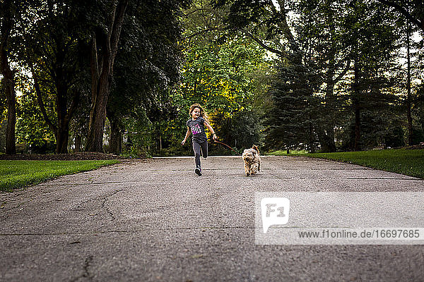 Mädchen läuft mit Hund an der Leine