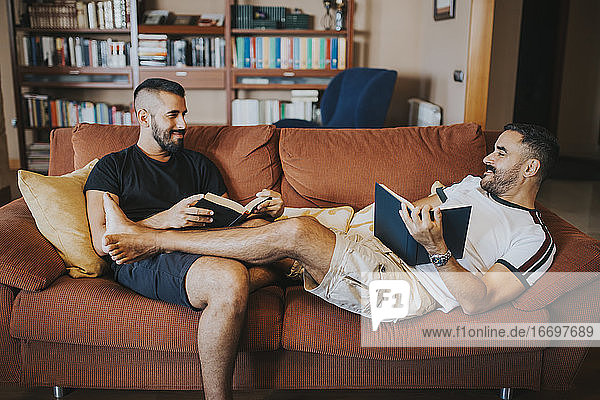 gay couple reading on the sofa with their legs on each other