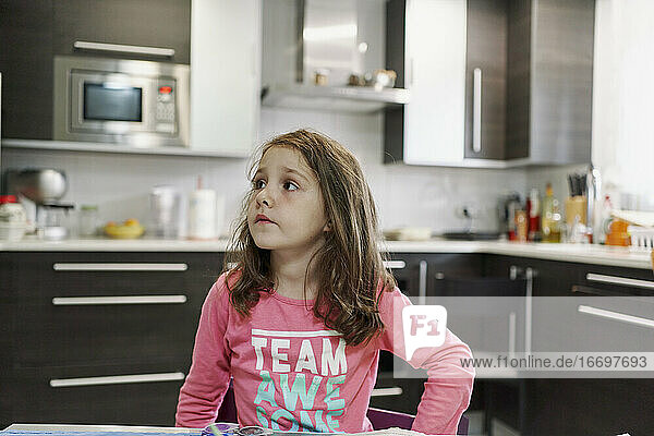 kleines Mädchen malt ein Aquarellbild in ihrem Haus mit der Küche im Hintergrund