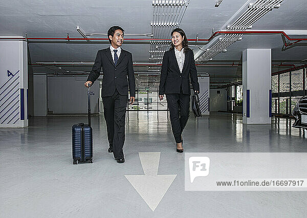 business couple walking through modern parking lot in Bangkok