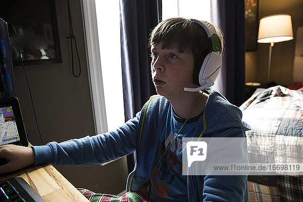 Close Up of Teen Boy Wearing Headphones Playing Gaming Computer
