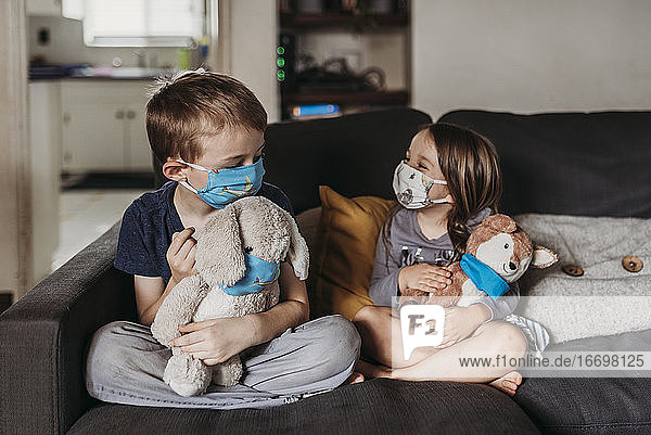 Vorschulalter Mädchen und Schule Alter Junge mit Masken spielen Spielzeug auf Couch