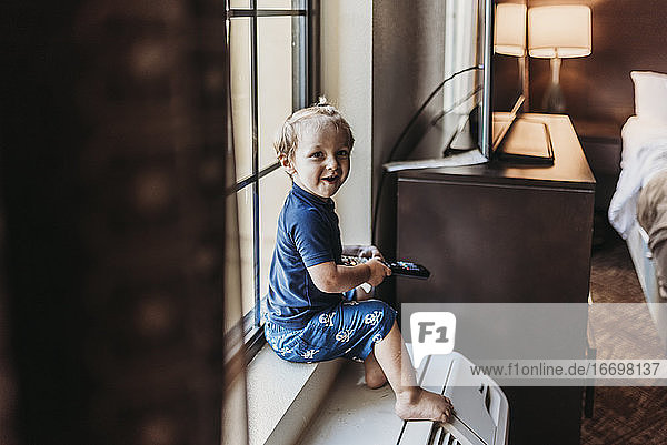 Young toddler boy sitting on window sill in hotel room in Palm Springs