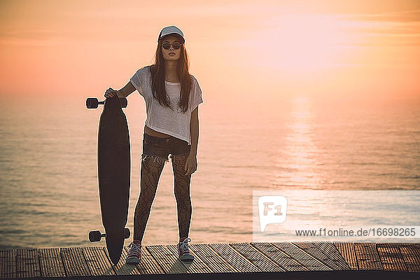 Schönes junges Mädchen mit ihrem Skateboard
