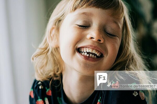 junges Mädchen mit einem wackeligen Zahn  das lächelt und seine Zähne zeigt