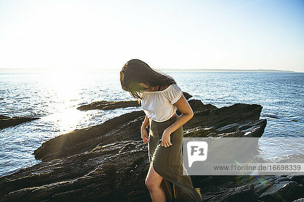 Young Latina Woman exploring by the ocean at golden hour in summertime