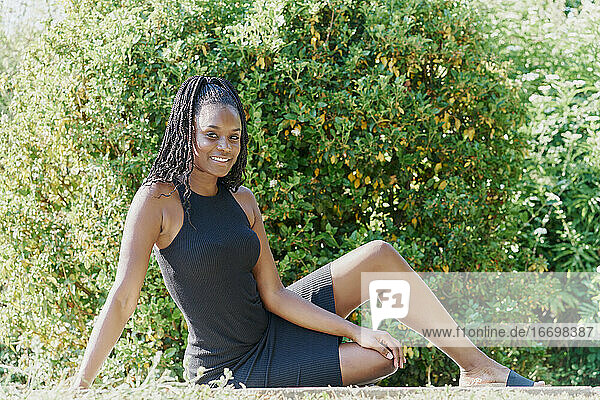 Porträt einer schönen schwarzen Frau  die auf dem Boden sitzend trinkt