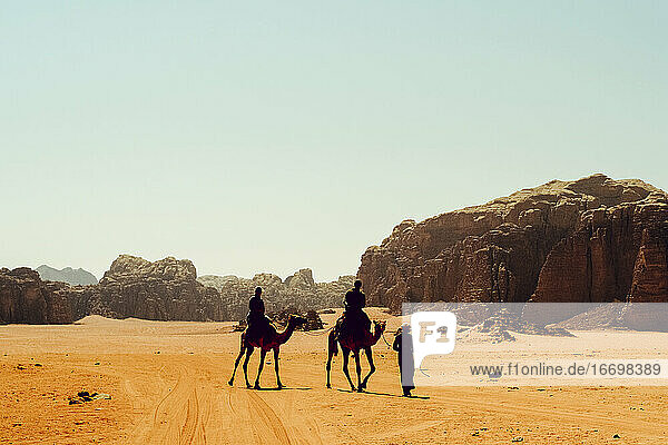 Touristen reiten auf Kamelen mit einem Beduinenführer in Wadi Rum  Jordanien
