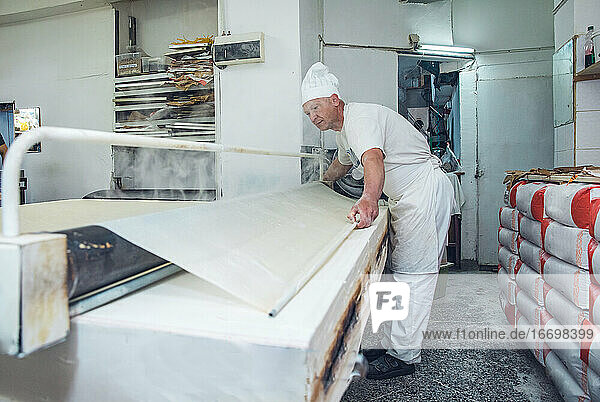 Mann rollt und dämpft Teig in einer Bäckerei in Belgrad  Serbien
