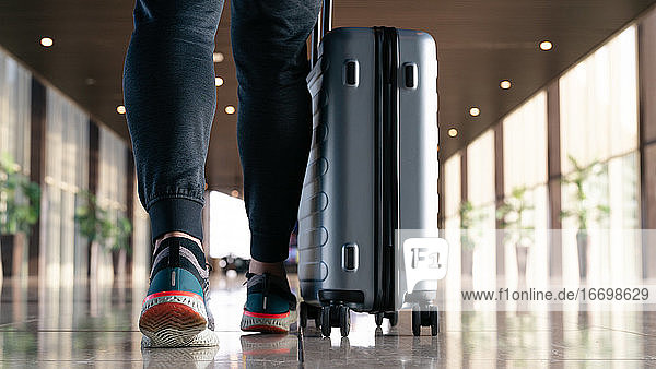Reisender mit Koffer  der mit Gepäck und Passagieren unterwegs ist