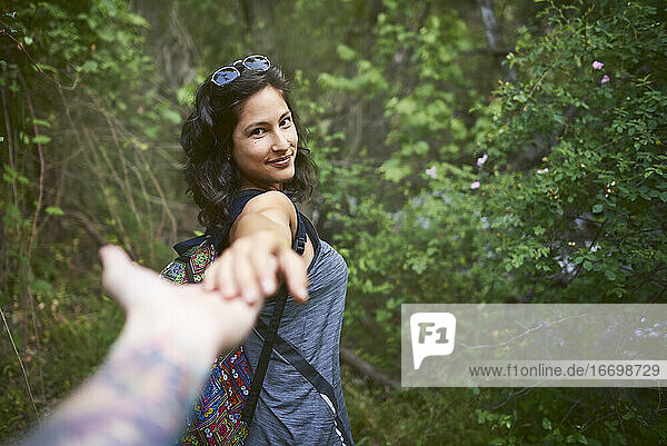 Porträt einer glücklichen jungen Frau  die die Hand ihres Freundes hält  während sie den Berg hinuntergeht