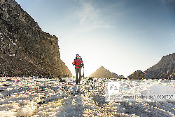 Bergsteiger mit Rückenbeleuchtung überquert Gletscher auf Baffin Island.