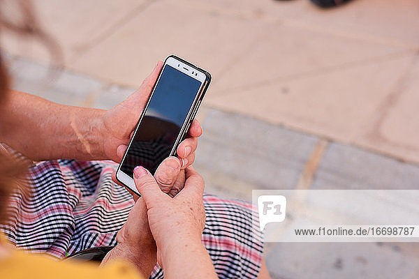 Nahaufnahme einer Frau mittleren Alters und ihrer Mutter  die ein Smartphone halten