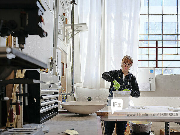 Professionelle Bildhauerin beim Mischen von Gips in ihrem Atelier