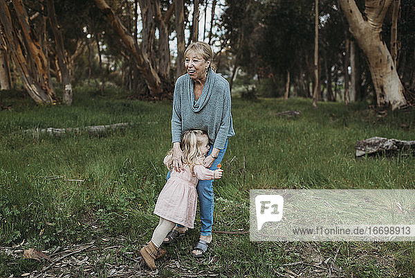 Young granddaughter running to hug grandmother in field