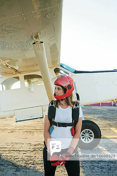 Junge Fallschirmspringerin auf einem Flugplatz mit einem Flugzeug im Rücken