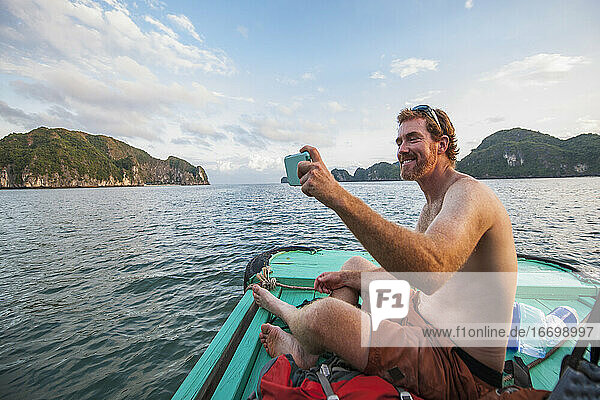 Mann macht Selfie auf einem Boot in der Halong-Bucht in Vietnam
