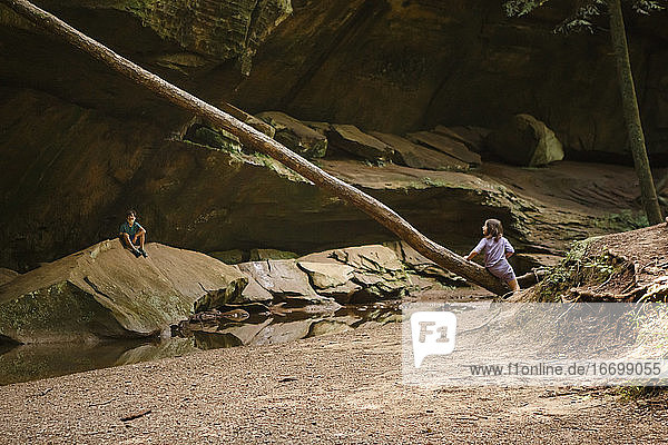 Two children play together in a rocky sandstone ravine by a stream