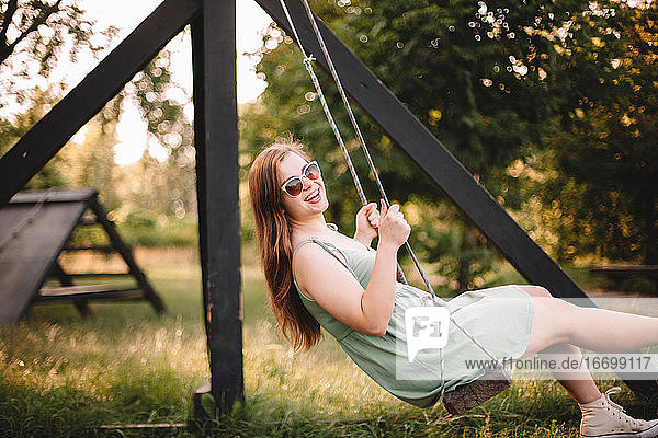 Happy young woman swinging in park during summer