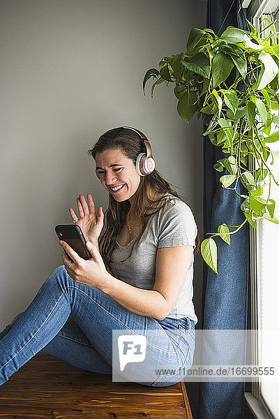 Lächelndes Porträt einer einzelnen Frau beim Facetiming von zu Hause aus