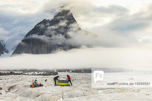 Zwei Bergsteiger unterhalb eines dramatischen Berges in der Arktis  Baffin Island