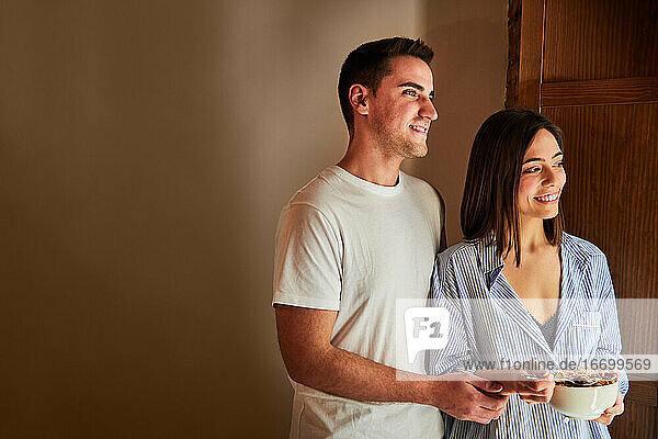 Young couple having breakfast next to a window at home. Copyspace