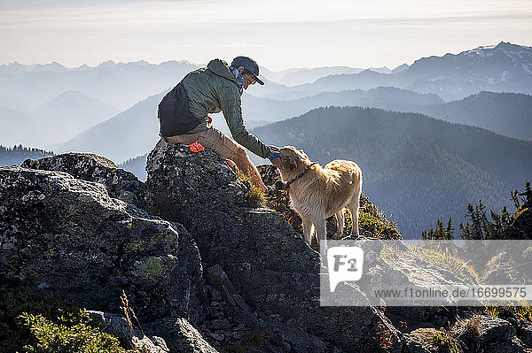 Male hiker and dog on summit of mountain in the cascades