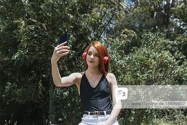 Porträt eines süßen Mädchens mit roten Haaren  das ein Selfie macht