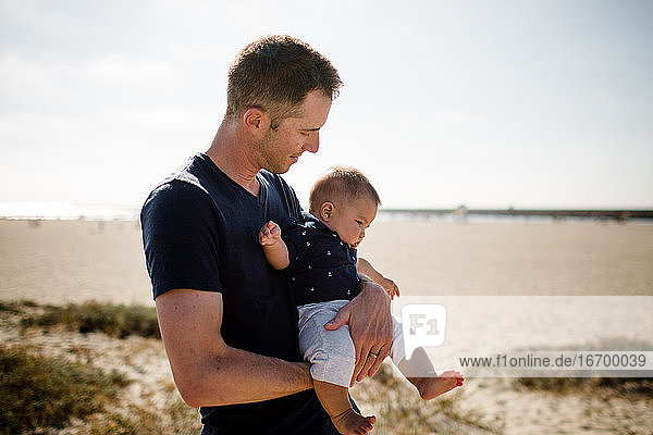 Father Cradling Infant Son on Beach