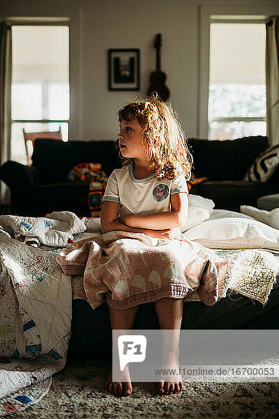 Junges Mädchen sitzt auf einer Luftmatratze im Wohnzimmer