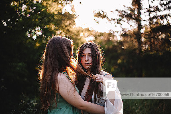 Young lesbian couple romancing while standing in forest during summer