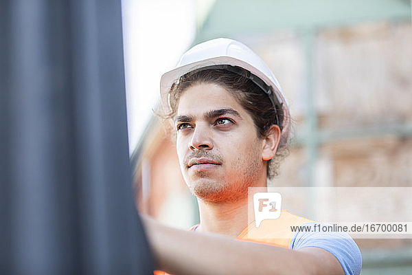 junger Angestellter mit Helm bei der Arbeit in einem Geschäft